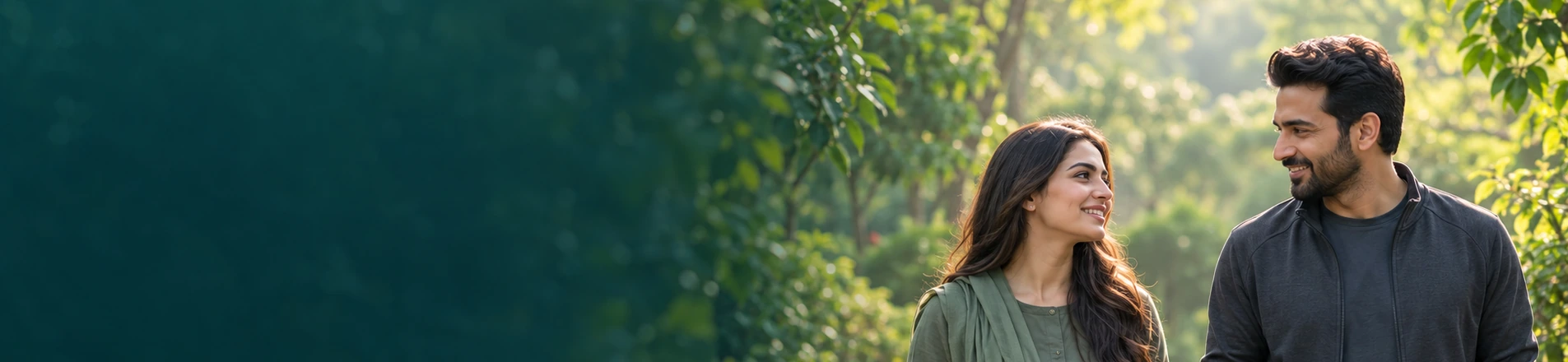 Two people walking and talking along a sunlit garden path, with foliage filling the left side of the frame